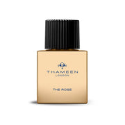 A bottle of Thameen London 'The Rose' perfume with a gold color and a black cap.